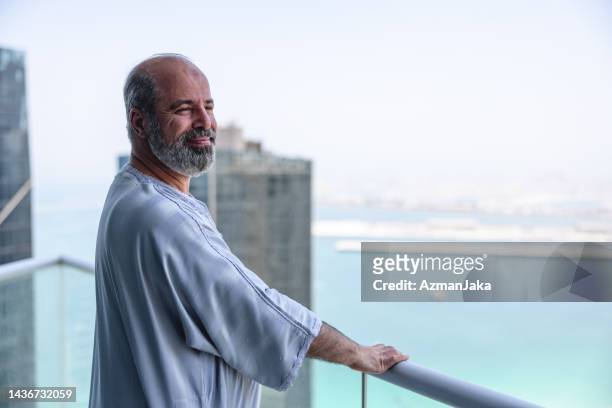 middle eastern older male enjoying view on his balcony - islam man stock pictures, royalty-free photos & images