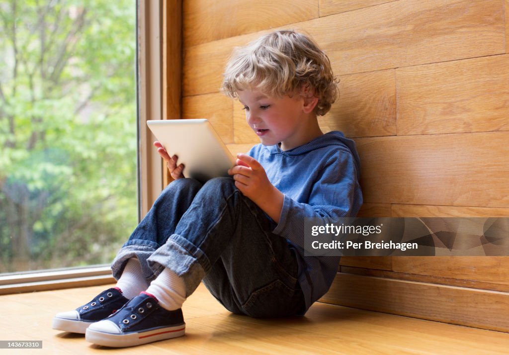 YOUNG BOY LOOKING AT TABLET COMPUTER