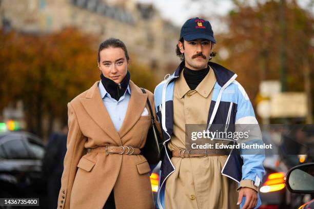 Influencers Young Emperors are seen. A guest wears a black zipper high neck pullover, a pale blue shirt, a black short skirt, a brown belted long...