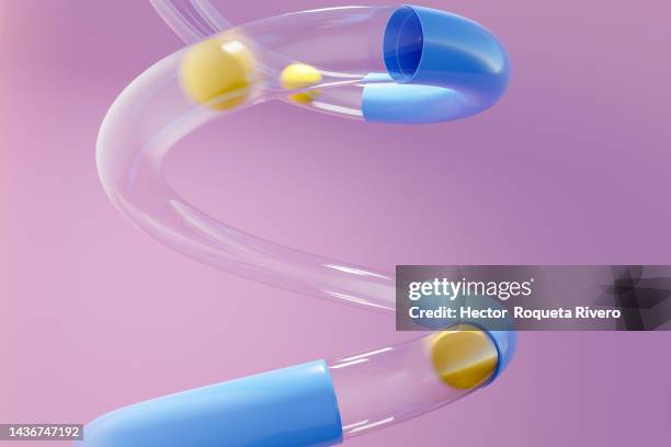 yellow balls passing through transparent and blue plastic tube on purple background - playful abstract stock pictures, royalty-free photos & images