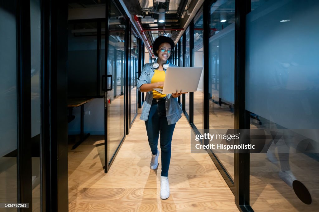 Happy IT technician working at the office using her laptop