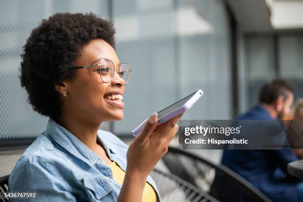 happy woman at work talking on speaker on her cell phone - voice command stock pictures, royalty-free photos & images