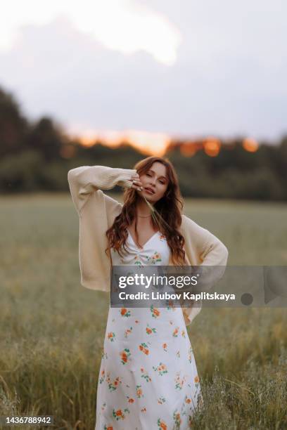 young woman with long hair posing while standing in a wheat field with tall grass. - cardigan photos et images de collection