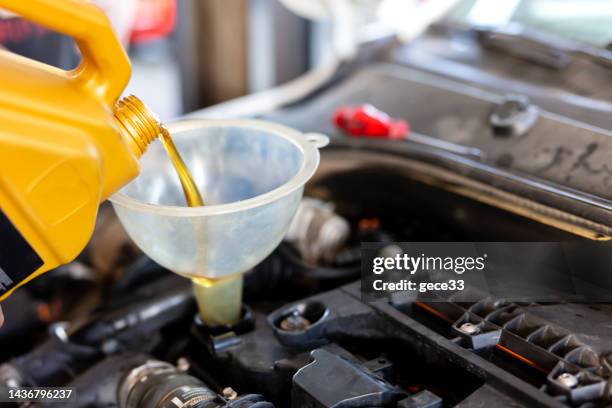 pouring motor oil for motor vehicles from a gray bottle into the engine - óleo-de-motor imagens e fotografias de stock