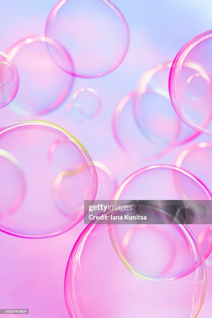 Colorful soap bubbles on pink and blue gradient background. Beautiful 3D vertical pattern. Festive backdrop.