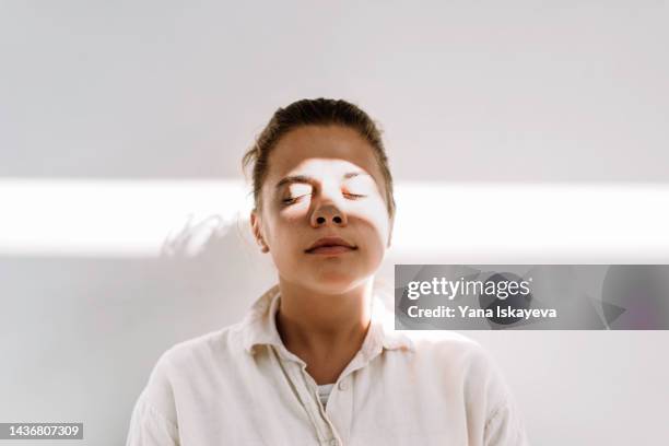 beautiful tanned woman enjoys the sun against white wall - mindfulness stock pictures, royalty-free photos & images