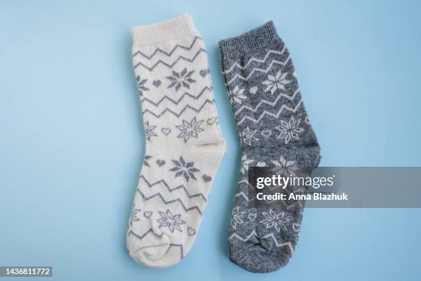 warm winter wool gray and white socks with christmas ornament on blue background - stocking feet fotografías e imágenes de stock