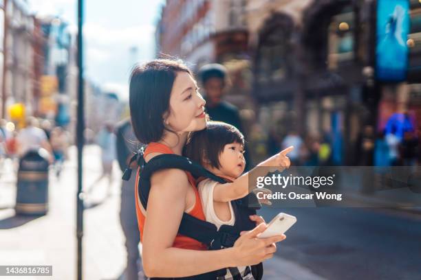 young asian mother exploring the city with her baby girl - baby pointing stockfoto's en -beelden