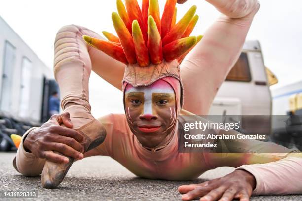 circus contortionist practicing his act by bending his legs forward and grabbing his foot in front of him. - buigen-lichaamsbeweging stockfoto's en -beelden