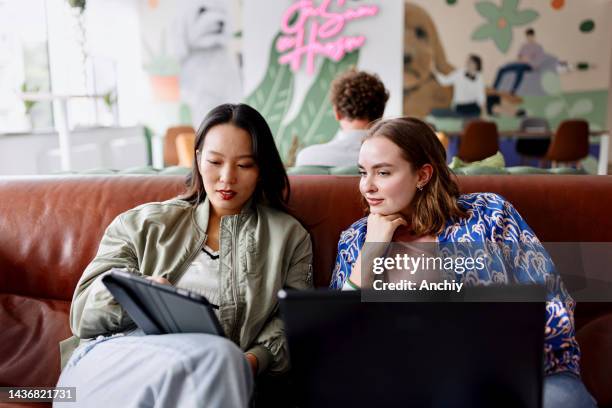 dos empresarias trabajando juntas en una oficina moderna - businesswoman couch fotografías e imágenes de stock