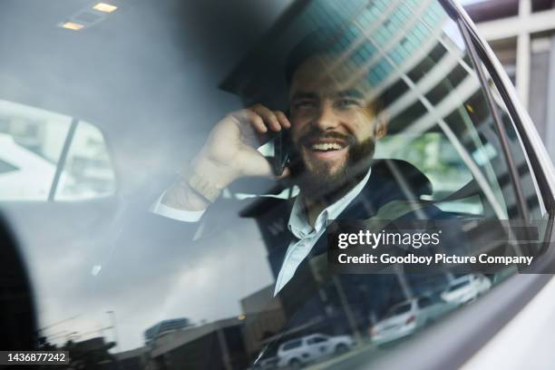 businessman talking on a phone and laughing while riding in a taxi - businessman driving stock pictures, royalty-free photos & images