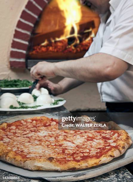 pizza sitting on spatula in kitchen - napoli pizza stock pictures, royalty-free photos & images