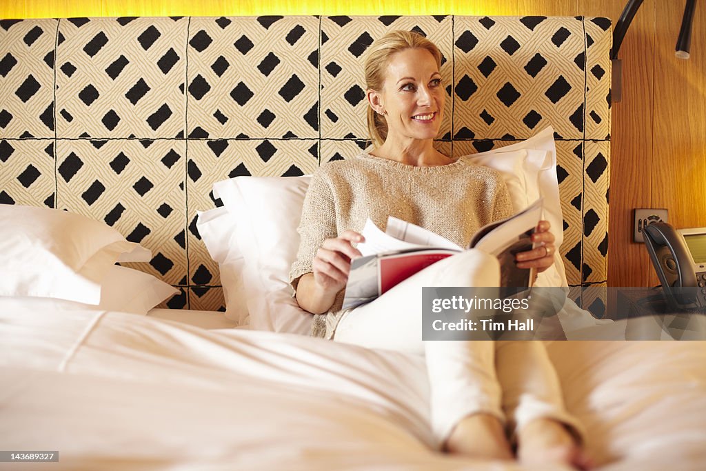 Woman reading magazine on bed