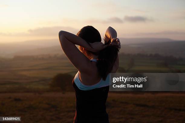 runner tying her hair in rural landscape - touching hair stock pictures, royalty-free photos & images