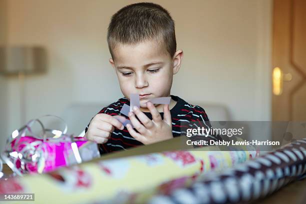 boy wrapping presents at desk - birthday gift stock pictures, royalty-free photos & images