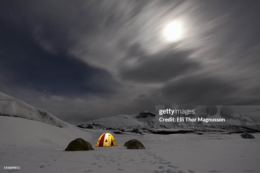 Illuminated tent at glacier campsite