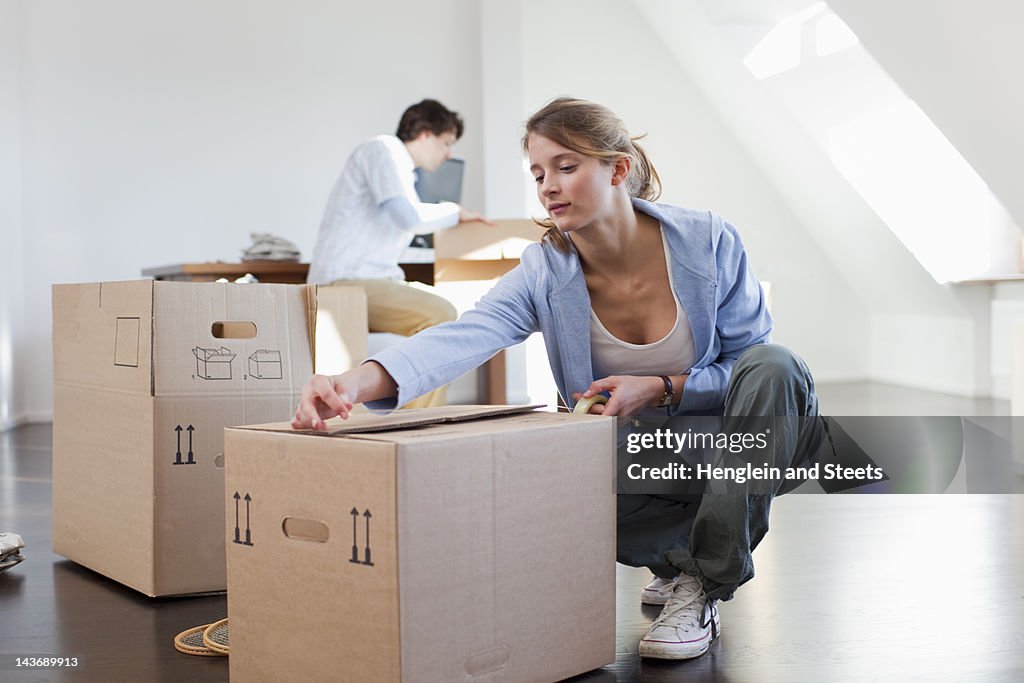 Woman taping up cardboard box