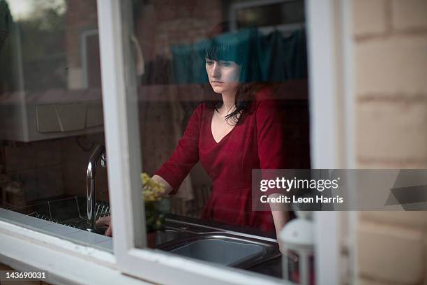 disappointed woman standing in kitchen - isolated women serieus sad stockfoto's en -beelden