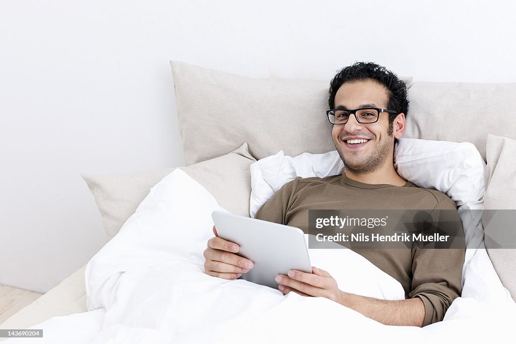 Man using tablet computer in bed