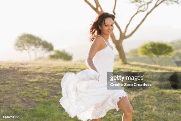 sonriente mujer caminando en campo - vestido blanco fotografías e imágenes de stock