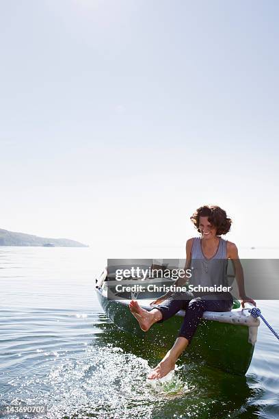 woman dangling feet from boat in lake - starnberger see stock-fotos und bilder
