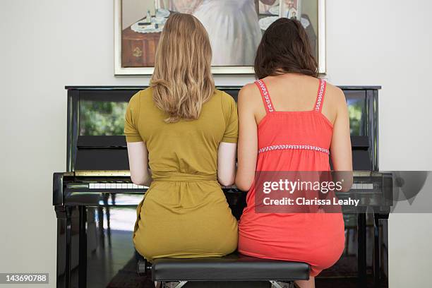 teenage girls playing piano together - duet stockfoto's en -beelden