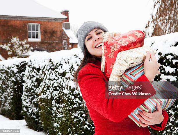 woman carrying wrapped gifts in snow - pile of gifts stock pictures, royalty-free photos & images