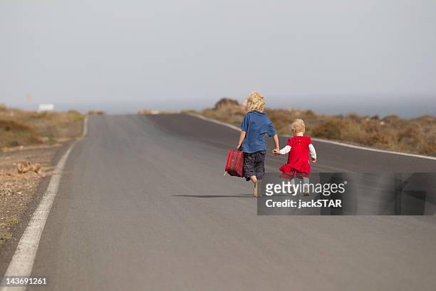 siblings walking together on rural road - runaway stock pictures, royalty-free photos & images