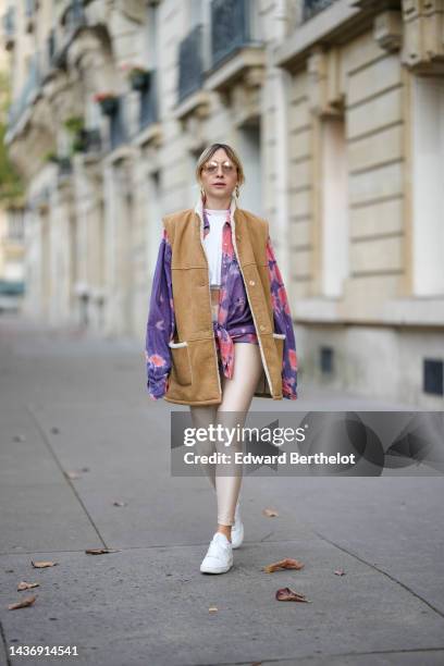 Emy Venturini wears gold aviator sunglasses from Prada, gold large earrings, a white cropped top from Prada, a pink and purple tie and dye print...