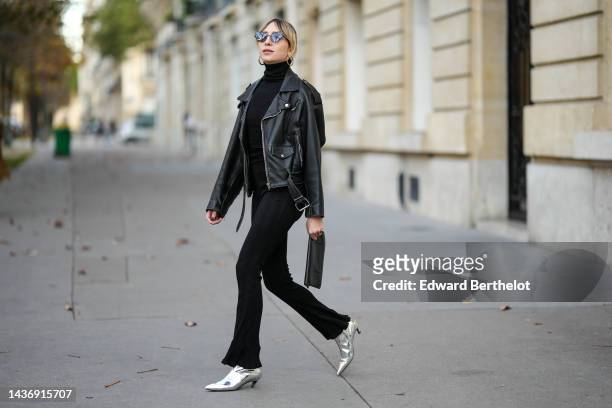 Emy Venturini wears black cat eyes sunglasses, gold earrings, a black ribbed wool turtleneck pullover from Intimissimi, a black shiny leather biker...