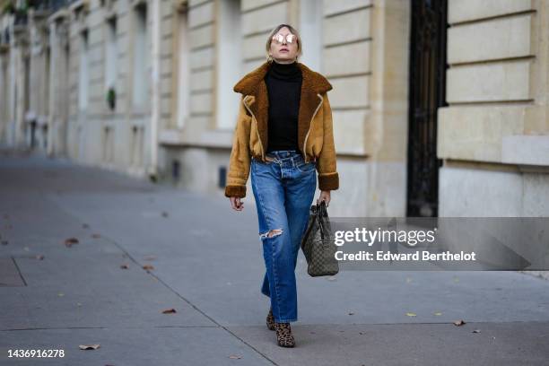 Emy Venturini wears a black ribbed wool turtleneck pullover, a yellow suede and brown sheep interior aviator coat from She Abbigliamento, blue...