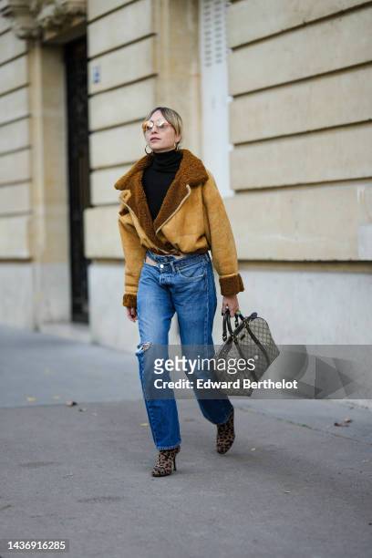 Emy Venturini wears a black ribbed wool turtleneck pullover, a yellow suede and brown sheep interior aviator coat from She Abbigliamento, blue...