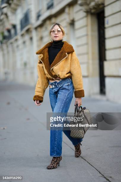 Emy Venturini wears a black ribbed wool turtleneck pullover, a yellow suede and brown sheep interior aviator coat from She Abbigliamento, blue...