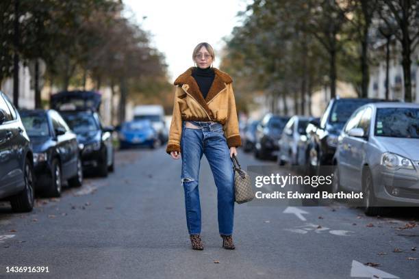 Emy Venturini wears a black ribbed wool turtleneck pullover, a yellow suede and brown sheep interior aviator coat from She Abbigliamento, blue...