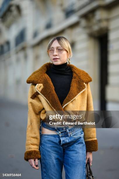 Emy Venturini wears a black ribbed wool turtleneck pullover, a yellow suede and brown sheep interior aviator coat from She Abbigliamento, blue...