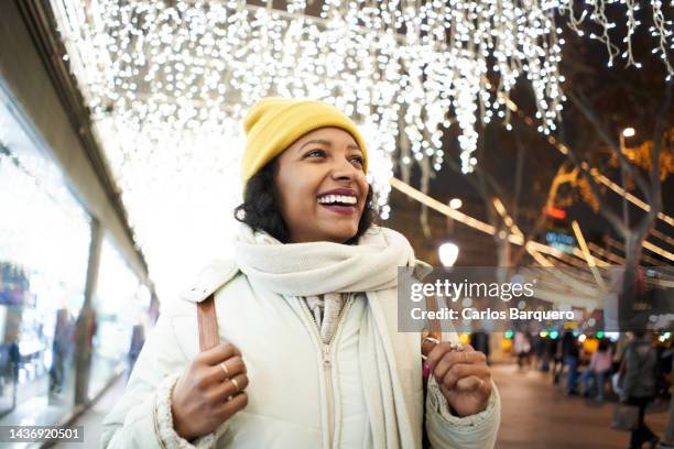 portrait of one woman looking at christmas decoration happily during the nightlife. - holiday shopping stock pictures, royalty-free photos & images