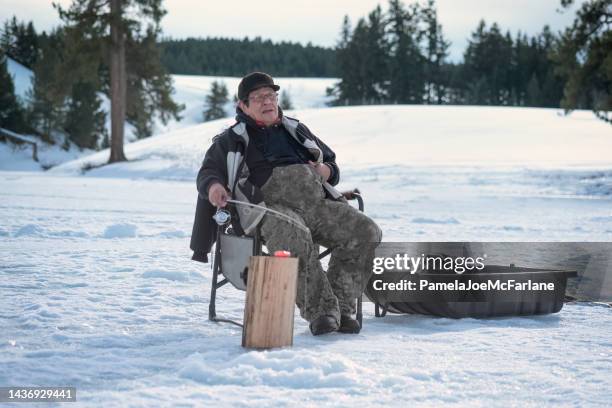 indigenous senior man ice fishing on frozen lake - senior winter sport stock pictures, royalty-free photos & images