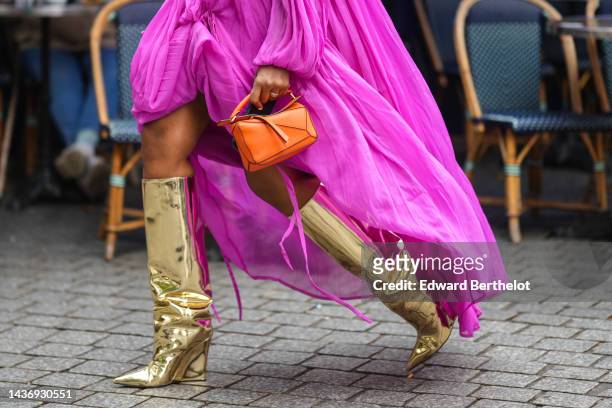 Guest wears a neon purple pleated / accordion long sleeves / knot wrap long dress, a neon orange shiny leather Puzzle handbag from Loewe, gold shiny...