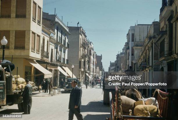 Pedestrians pass a cart and trucks on a street in the town of Castellon de la Plana, capital of the province of Castellon on the Mediterranean coast...