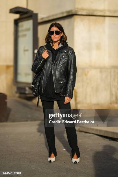 Guest wears black sunglasses, a white t-shirt, a black hoodie sweater, a black shiny leather Chanel 22shoulder bag from Chanel, a black shiny leather...