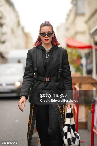 Guest wears black cat eyes sunglasses, silver earrings, silver large chain necklaces, a black blazer jacket, a black fabric belt, a black hoodie...