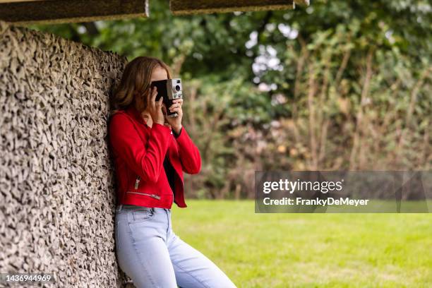 young woman using old analog throwback vintage retro movie camera outdoors in the garden - photo de film stock pictures, royalty-free photos & images