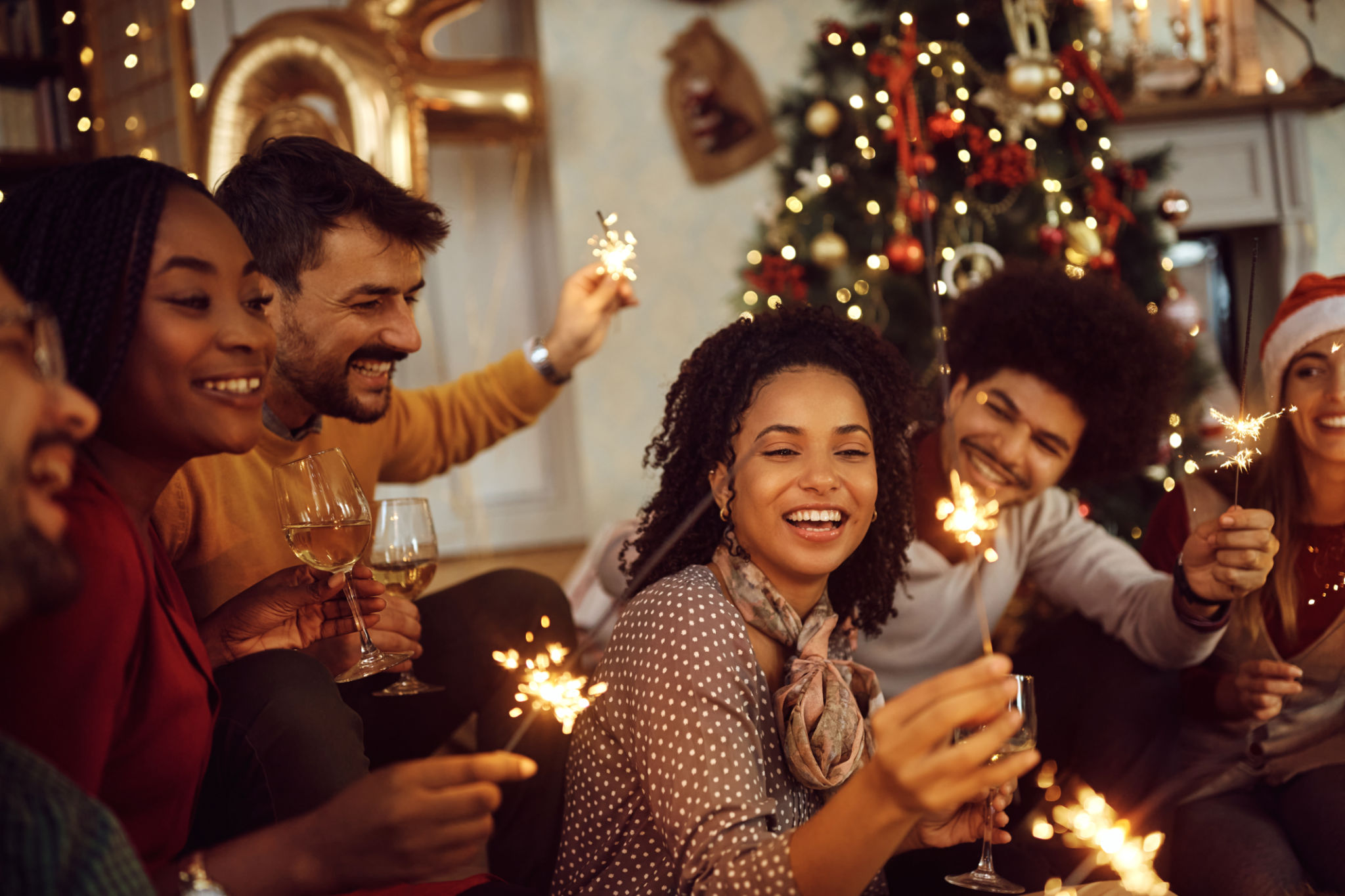 Multiracial group of happy friends using sparklers and having fun on New Year's day at home. Multiracial group of happy friends using sparklers and having fun on New Year's day at home.