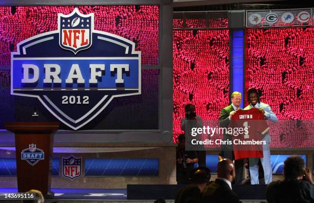 Robert Griffin III from Baylor holds up a jersey as he stands on stage with NFL Commissioner Roger Goodell after Griffin was selected overall by the...