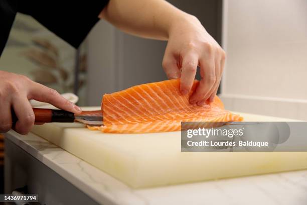 close-up of master chef cutting fish on a kitchen board - nigiri stock-fotos und bilder