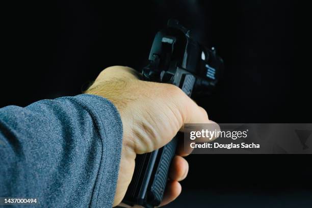 human hand aims the gun - bankräuber stock-fotos und bilder