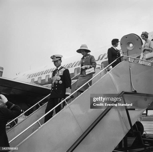 King Bhumibol Adulyadej and Queen Sirikit of Thailand walking down airplane steps at Gatwick Airport in London for a state visit to the United...