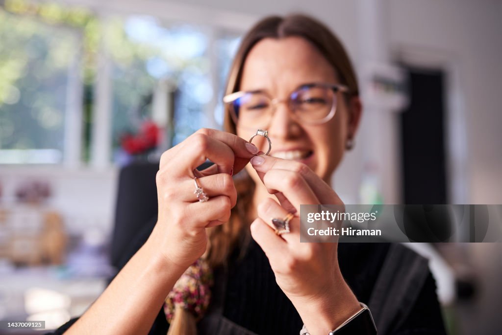Frau, Schmuck und Designer inspizieren Ring im Studio auf Mode, Qualität oder Glanz von Schmuck. Kreativ, Mädchen und Schmuck mit Lächeln für Design in Werkstatt, Arbeitsplatz oder Büro während glücklich im Job