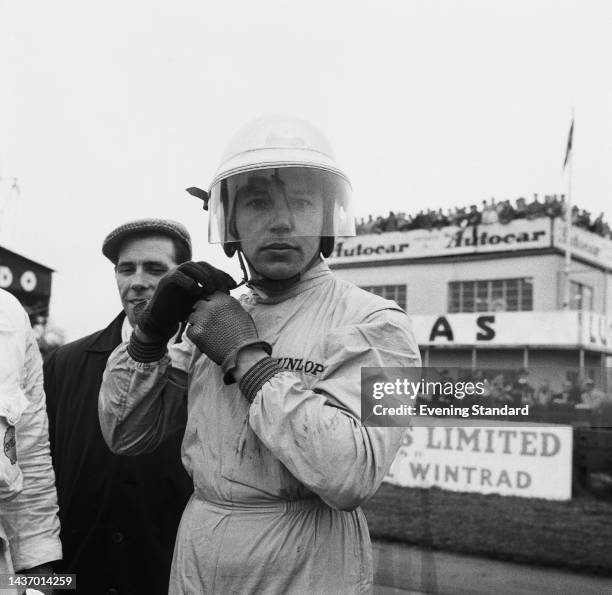 British racing driver John Surtees fastening his helmet at the Glover Trophy race at Goodwood Circuit, West Sussex, on April 3rd, 1961. Surtees went...