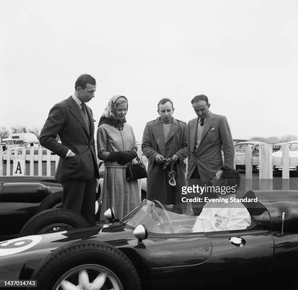 The Duke of Kent, his fiancée Katharine Worsley, racing driver John Surtees and an unidentified man talk with Roy Salvadori who is sitting in his...